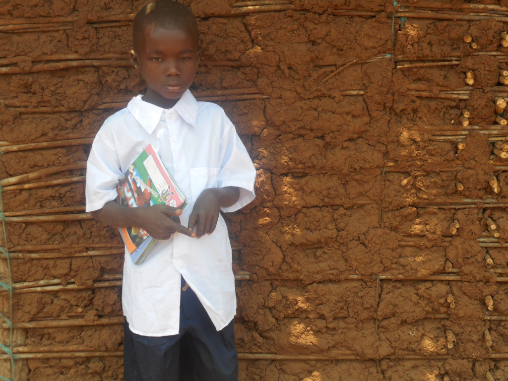 Hekima outside his home with new uniform & books