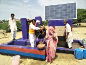 A woman filling her water pot from solar well