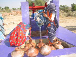 A woman filling water pitcher from the well