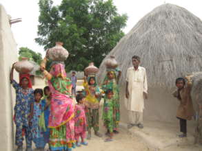 The women happily carrying water from the well.