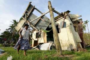 Fijia Woman with her home in ruins