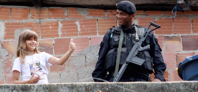Little girl and a policeman carrying heavy weapon