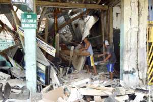 Men stand in rubble of building
