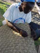 A kenyan woman weaves a floor mat