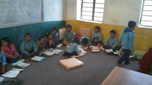 Kindergarteners sit on pillows on the carpet