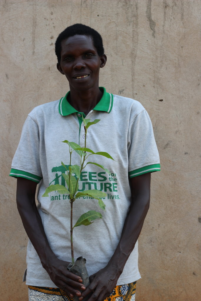 A farmer shows off her mango seedling