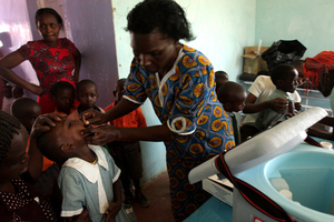 Naiomi Meme (right) administers a Vitamin A supplement