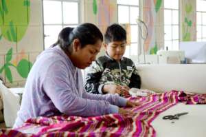 Karina sewing alongside her son (elperiodico.com)