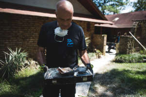 Head of Mission holding fragments of a household