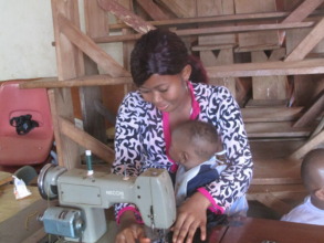 Trainee sewing with child in hand