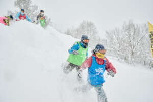Kids race down a snowy hill at snow program