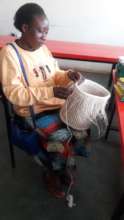 A Jitegemee mother focused on her basket-weaving