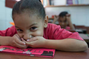 Student with a roguish smile at her desk