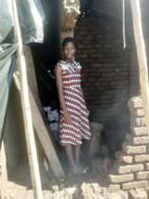 AGE Africa Scholar standing in damaged home