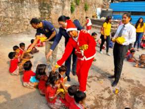 Santa Claus distributing fruits to the kids