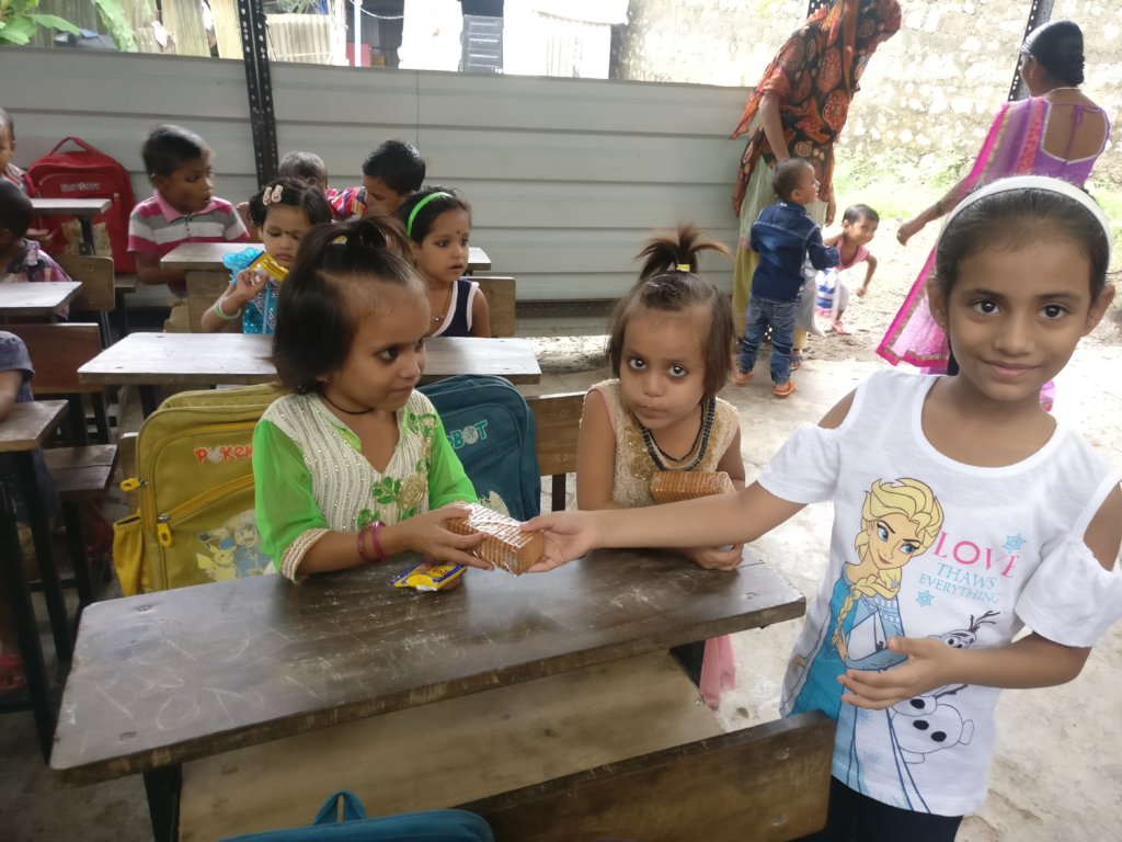 Ananya & Ritika distributing sweets to tiny-tots