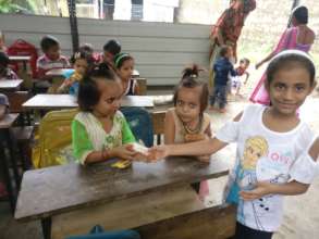 Ananya & Ritika distributing sweets to tiny-tots