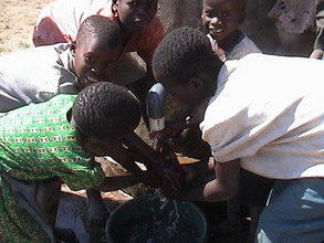Children washing their hands in the spout of the Elephant pump