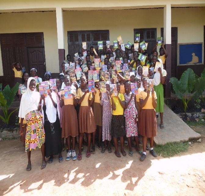 a group of teen girls pose infront of their school with their books