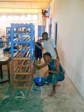 Tz school student volunteers painting the shelves