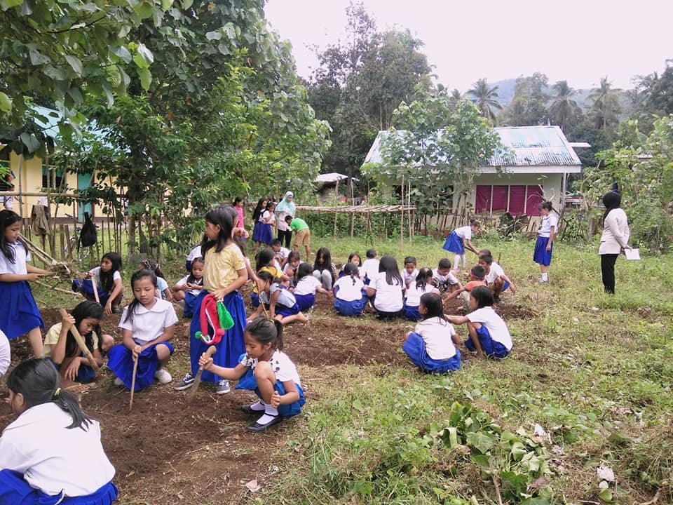 Girls working with their teachers to prep garden