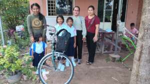 Beneficiaries with bicycle and study materials