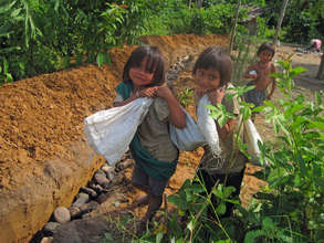 Children carrying rocks to build thier drain.