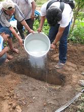 Villagers conducting ground percolation test for greywater drain