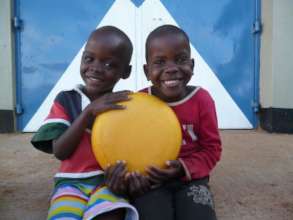 Children and a wheel of cheese at the Baraka Farm