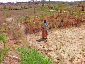 Esther standing on her drought-cracked land.