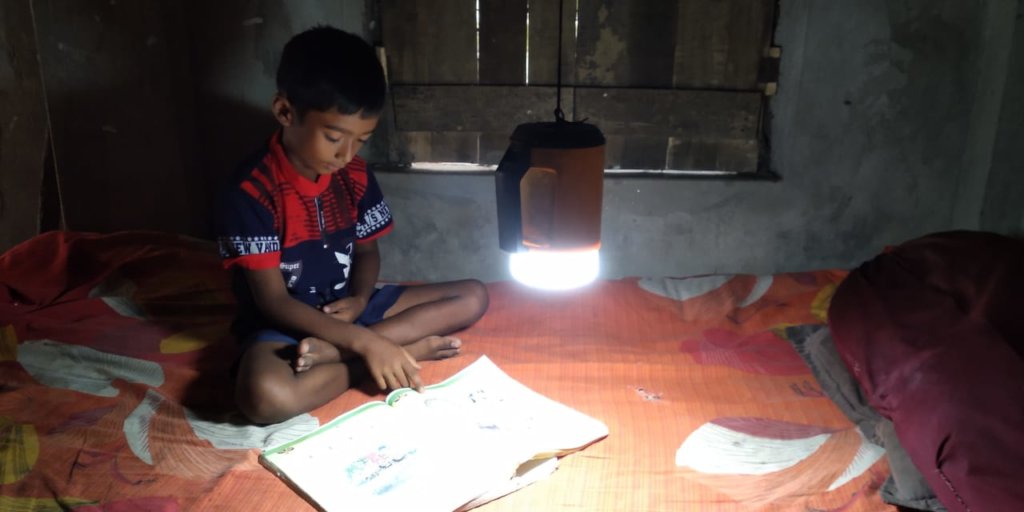 Poor students reading using solar lamp