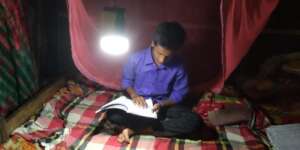 Poor student using solar lamp for reading at night