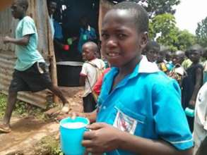 A boy having his cup of porridge at school