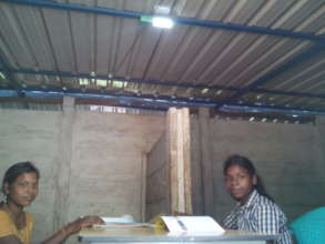 two children reading from solar lantern