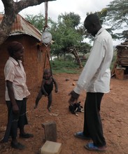 A CHW weighing a child with a hanging Salter scale