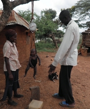 A community health worker weighing a child
