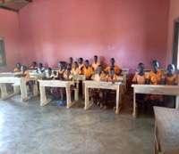Pupils siting on donated furniture in classroom