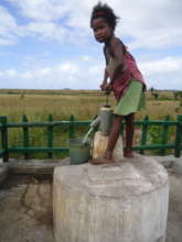Young girl pumping water at a community well