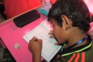 A boy practices writing Arabic on the Hope Bus