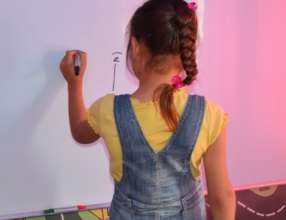 A young girl practices writing on the Hope Bus