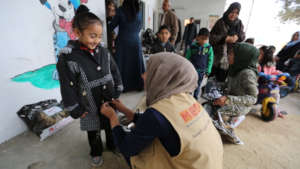 Buttoning up a new coat for a child in Gaza