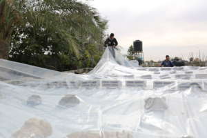 Volunteers cover the roof of a home in Gaza