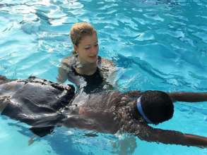 A volunteer coaching a local in swimming