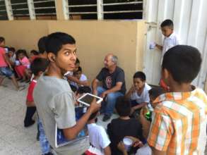 Volunteer, Paul C, sitting with students