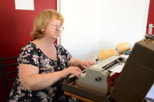 Moza prepares lessons on a Braille typewriter