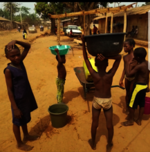 More community residents accessing water source.