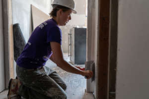 Site Supervisor Emily mudding a corner of a room