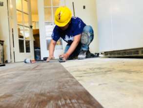 A volunteer lays waterproof flooring at a home
