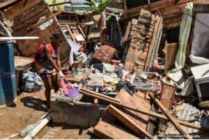 A girl in Dominica pulls a bag from the wreckage