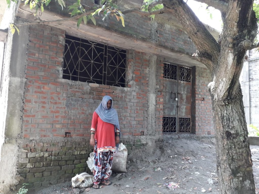 Hasina Khatoon in front of her house
